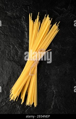 Raw spaghetti tied with rope on black background Stock Photo