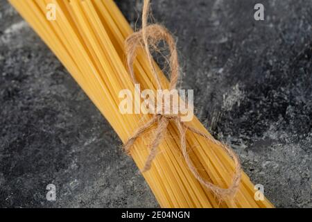 Dry spaghetti tied with rope on marble background Stock Photo