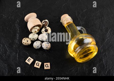 Fresh farm quail eggs and olive oil on black background Stock Photo