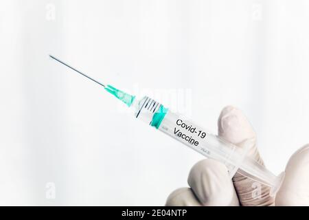 Male hand in white gloves holding a plastic syring with covid-19 vaccine, vaccination concept Stock Photo