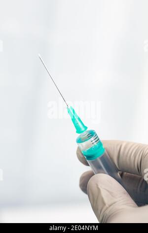 Male hand in white gloves holding a plastic syring with liquid for injection isolated on white background. Stock Photo