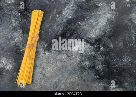 Dry spaghetti tied with rope on marble background Stock Photo