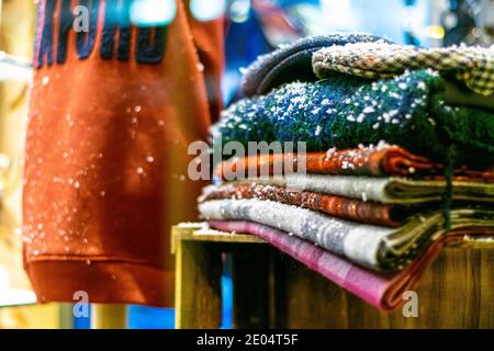 Oxford, UK -14 Dec 2020: Winter blankets and jumpers with snow, all stacked on each other, red bag in the background, shop display for snowy but cosy Stock Photo