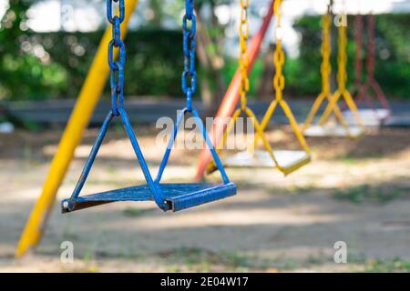 Row of multi-colored chain swing in kid playground on front focus. Stock Photo