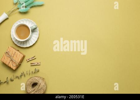 Gift box, cup of coffee with dry plant on khaki background. flat lay, top view, copy space Stock Photo