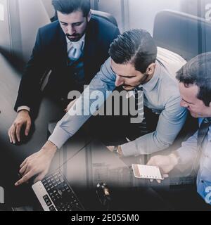 Businessmen trading stocks. Stock traders looking at graphs, indexes and numbers on multiple computer screens. Colleagues in discussion in traders Stock Photo