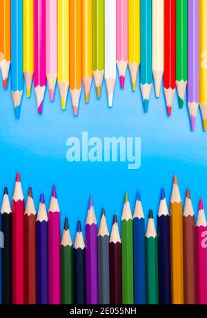 Color pencils on blue background, top view with space for text or creativity.Light and dark pencils. Stock Photo