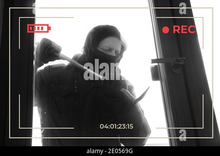 View of a CCTV house breaking through a door with a crowbar. Stock Photo