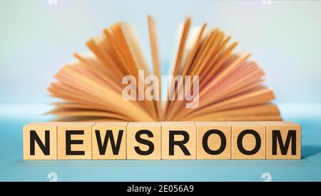 Wooden cubes with the abbreviation NEWSROOM on the background of an open book. Stock Photo