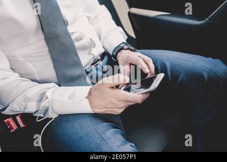 Close up of businessman using mobile smart phone in a car. Stock Photo