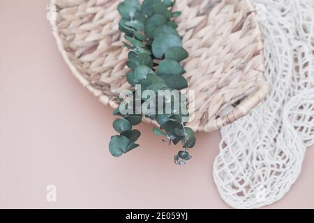 Wicker straw basket made of recycled materials. grocery mesh string eco bag.  sustainable shopping and home. recycled material gifts. eucaliptus leaves  Stock Photo - Alamy