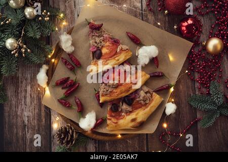 Flat Lay pizza laid out in the form of a Christmas tree on a wooden tray with a garland and Christmas decorations, Happy New Year Stock Photo