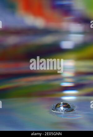 drop impacting in colorful liquid and dripping with crown Stock Photo