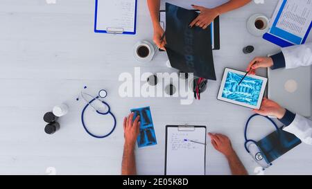 Top view of fast forward shot of doctors having medical conference sitting on desk using digital technology, taking notes, researching and checking appointments. Copy space flat lay time lapse concept Stock Photo
