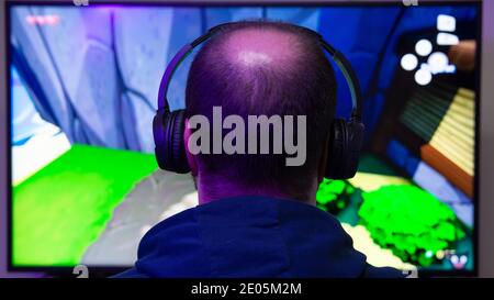 Close-up of a man from behind in front of a screen playing a video game. Gamer and e-sports concept. Vertical photography and copy space. Stock Photo
