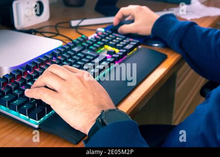 Close-up of a man's hands typing on a computer keyboard and using the mouse. Concept of teleworking from home, due to the Covid-19 pandemic. Horizonta Stock Photo