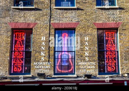 Neon signs in the windows of Hanks Acoustic Guitars shop on famous music shop street - Denmark Street, London, UK Stock Photo