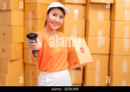 Asian parcel delivery worker in warehouse with barcode scanner. Stock Photo