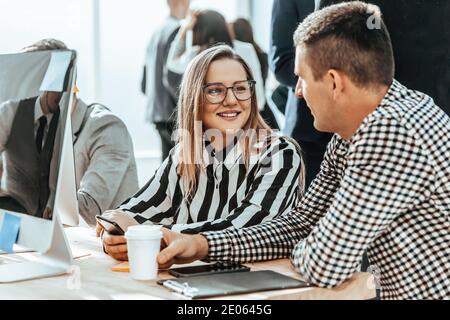 colleagues discussing something sitting at a table in the office Stock Photo