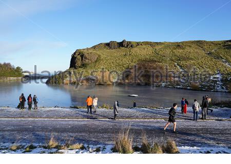 Edinburgh, Scotland, UK. 30th Dec 2020. People enjoying the outdoors and Snow in Holyrood Park, seen here at a frozen Dunsapie Loch and Dunsapie Hill. Credit: Craig Brown/Alamy Live News Stock Photo