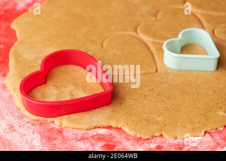 Dough for making heart shaped cookies on Valentines Day. Homemade pastry. Red and green plastic baking molds. Stock Photo