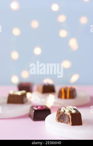 Hand decorated chocolate candy bonbons and pralines desserts on pink and blue background with lights bokeh Stock Photo
