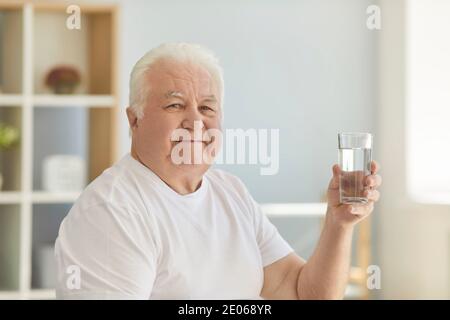 Positive senior man keeps healthy preventing dehydration by drinking enough water Stock Photo