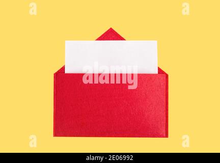 Red open envelope with a sheet of paper with mock-up on a yellow background with copyspace. Valentines day holidays concept and love notes Stock Photo