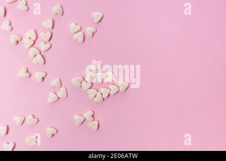 Sugar heart shaped sprinkles on pink background Stock Photo