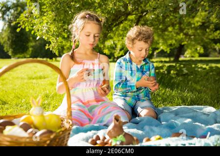 Cute boy and girl celebrating Easter, searching and eating chocolate eggs. Happy family holiday. Happy kids laughing, smiling and having fun. Stock Photo