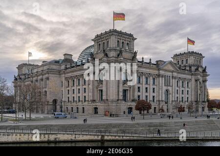 December 28, 2020, Berlin, the Reichstag building by master builder Paul Wallot on the Platz der Republik with flags on the day with cloudy skies. The Reichstag is the seat of the German Bundestag with plenary area. Side view from the Spree side. | usage worldwide Stock Photo