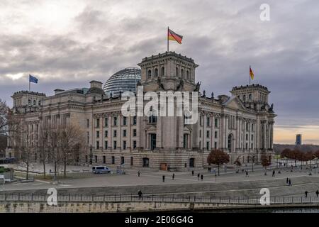 December 28, 2020, Berlin, the Reichstag building by master builder Paul Wallot on the Platz der Republik with flags on the day with cloudy skies. The Reichstag is the seat of the German Bundestag with plenary area. Side view from the Spree side. | usage worldwide Stock Photo