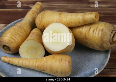 Close up of group raw isolated sliced parsnip root vegetables on blue china plate Stock Photo