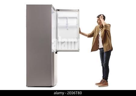 Young man in panic looking at an empty fridge isolated on white background Stock Photo