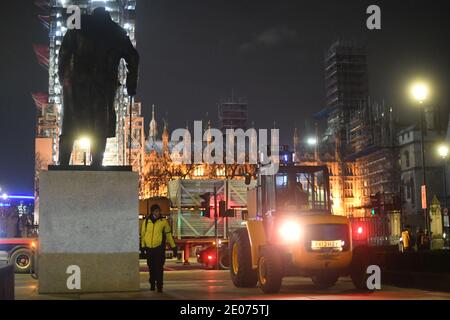 Construction workers put up fencing around the statues in Parliament Square, London, ahead of New Year's Eve. People are being urged to stay home on New Year's Eve to prevent the "dire" situation in hospitals from getting worse. Stock Photo