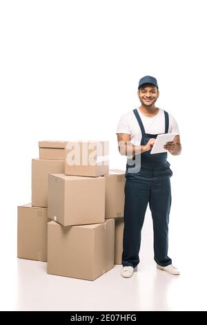 cheerful indian mover in overalls using digital tablet near carton boxes on white Stock Photo