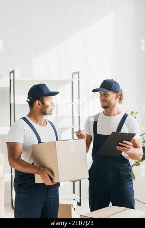 happy mover smiling while looking at indian worker and giving pen Stock Photo