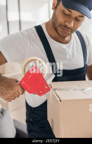 Indian mover in uniform packing box in apartment Stock Photo