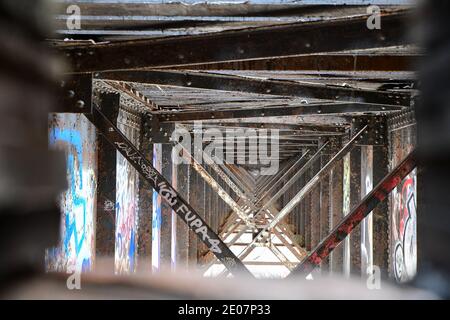 street art graffiti on the rusty old iron railway bridge and steel grid supports Stock Photo