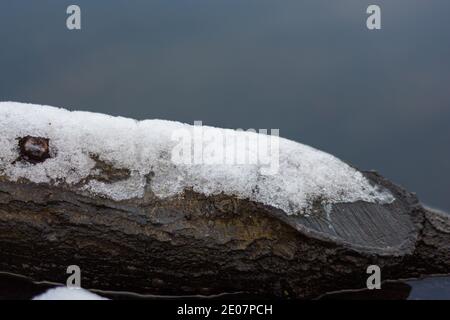 Ice formed from melting snow on a cut wooden branch Stock Photo