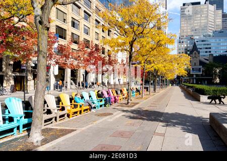 People resting on colorful chairs on the King street West looking East from John St. in autumn in Toronto, Canada. Stock Photo