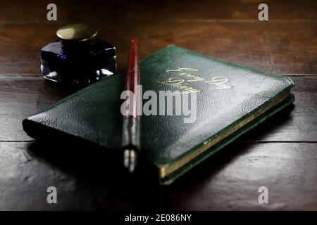 closed diary with dib pen and inkwell on desktop Stock Photo