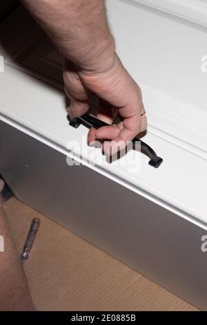 assembly of wooden furniture, white cabinet of a kitchen set. Carpenter services. Stock Photo