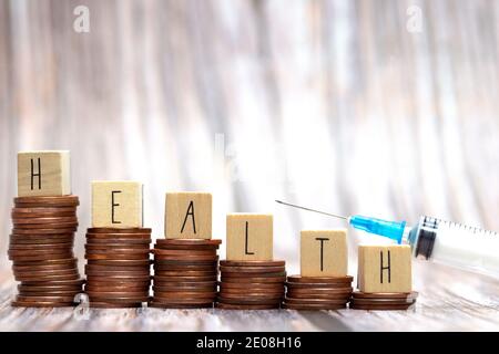 Word HEALTH on step stacked coins with syringe for injection, Money savings or investment planning for life insurance and healthcare concept. Stock Photo