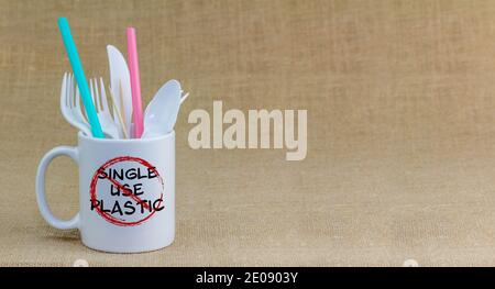 Single use plastic text crossed out on mug of  single use plastic items, refuse single use plastic cultery and straws. Stock Photo