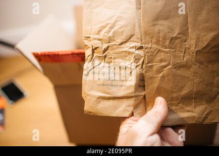 Paris, France - Dec 8 2020: POV male hand holding packaging Storopack paper plus for parcels with slogan Reuse, REduce and Recycle Stock Photo