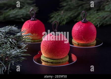 Three mousse desserts in the form of Christmas balls on a dark background. New Year party. Stock Photo