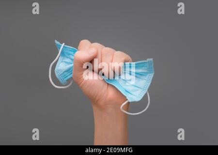 Fight to virus. Recovery from illness. New normal. Quarantine is over. After Covid-19. Victory coronavirus. Pandemic end. Mask in fist. Victory hand Stock Photo