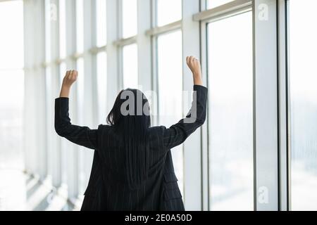 Confident businesswoman spreading hands standing at office window, enjoying big city, successful entrepreneur celebrating business success with arms o Stock Photo