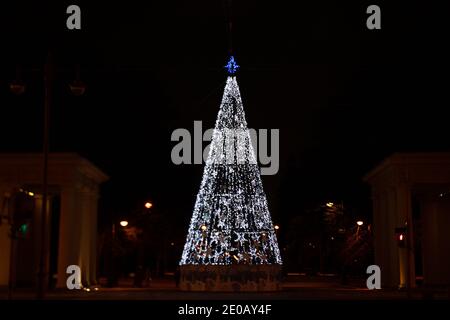Christmas/ New Year tree with white LED lights and blue topper against dark night background in St. Petersburg, Russia Stock Photo